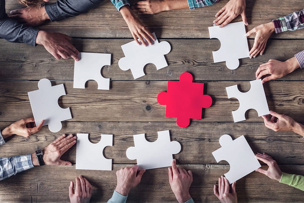 persone costruiscono un puzzle bianco con un pezzo rosso